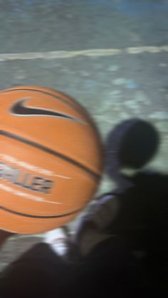 a person holding a basketball in their hand on the ground and blurry image behind them