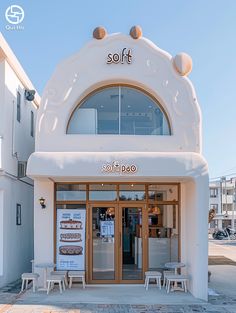 a white building with two tables and chairs in front of the door that says soft poo