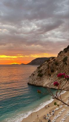 the sun is setting over an empty beach with lounge chairs and umbrellas on it