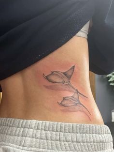 a woman's stomach with a tattoo design on the side, showing two flowers