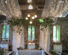 an indoor wedding venue decorated with lights and greenery