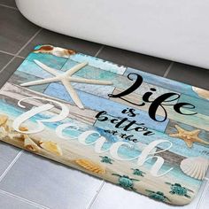 a bathroom rug with the words life is better at the beach and starfish on it