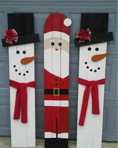 two snowmen made out of wooden planks with red bows