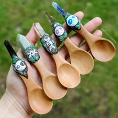 four wooden spoons with skulls on them are held in a person's hand