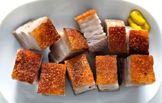 several pieces of food on a white plate with a yellow pickle in the background