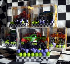 three clear boxes filled with green and purple candies next to black and white checkered wall