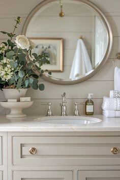 a bathroom sink with a mirror above it and flowers in a vase on the counter