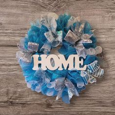 a blue wreath with the word home on it and bows hanging from it's side