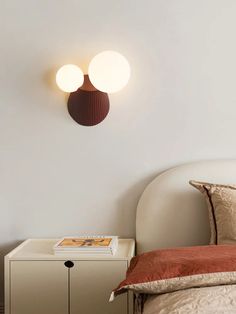 a bed with two lamps on the wall above it and a nightstand in front of it