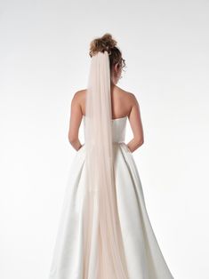 the back of a bride's wedding dress, with her veil blowing in the wind