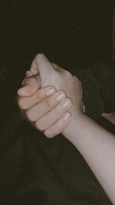 two people holding each other's hands with their arms wrapped around one another in the dark