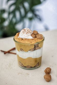 a dessert in a glass with nuts on the side