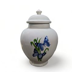 a white vase with blue butterflies painted on it