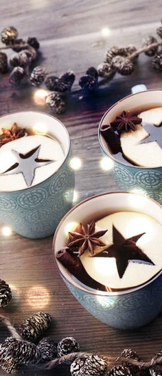 two mugs filled with hot chocolate and star decorations on top of a wooden table