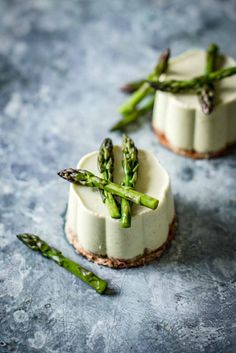 two small desserts with asparagus on top of each other, sitting on a table