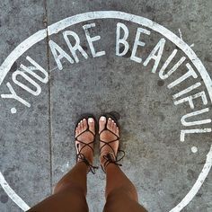 someone standing in front of a sign that says you are beautiful