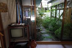 an old tv sitting on top of a wooden stand in front of a glass door