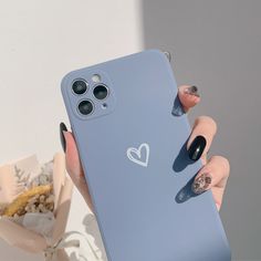 a woman's hand holding up a blue phone case with heart stickers on it