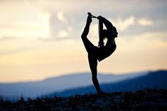 a woman doing yoga on top of a hill at sunset with mountains in the background