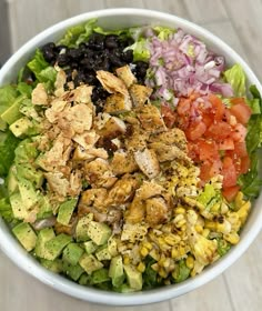 a salad with chicken, lettuce, tomatoes, black beans, corn and avocado