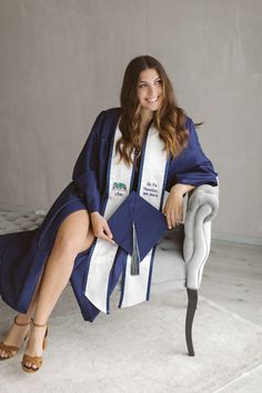 a woman sitting on a chair wearing a graduation robe