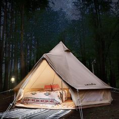 a tent is set up in the woods at night with lights on and stars above