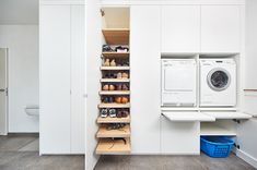 a washer and dryer sitting in a room next to some shelves with shoes on them