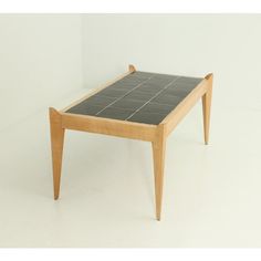 a small wooden table with black tiles on it's top and legs, against a white background