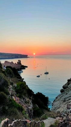 the sun is setting over the ocean with boats in the water