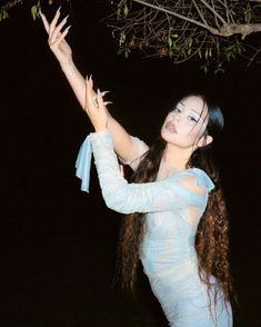 a woman in a blue dress is holding her arms out and looking up at the sky