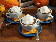 three cups filled with whipped cream sitting on top of blue and yellow placemats