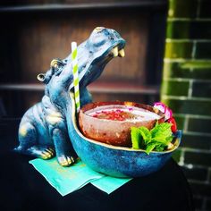 a blue ceramic frog drinking out of a bowl with a straw in it's mouth