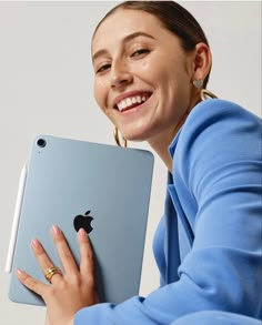 a woman smiles while holding an ipad