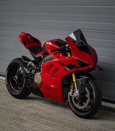 a red motorcycle parked in front of a garage door