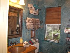 a bathroom with a toilet, sink and window covered in towels hanging on the wall