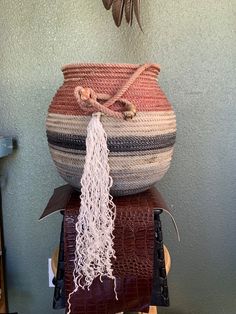 a large woven basket sitting on top of a wooden table next to a planter