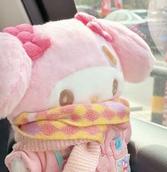 a hello kitty stuffed animal sitting in the back seat of a car with a scarf around it's neck