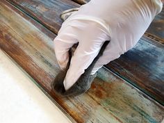 a gloved hand with white gloves on top of a wooden floor next to a piece of wood