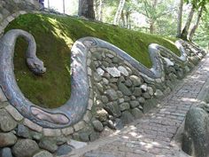 a stone wall with a snake carved into it's side and moss growing on top