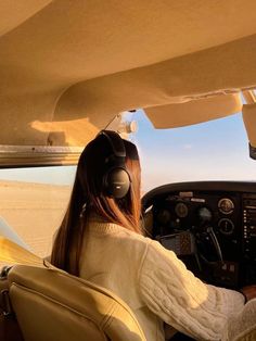 a woman is sitting in the cockpit of an airplane with headphones on and looking out the window