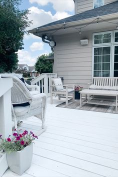 a white wooden deck with chairs and flowers on it