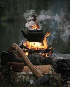 a tea kettle is on fire in the middle of an outdoor campfire with wood and logs