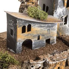 a model of a house with moss growing out of it's roof and windows