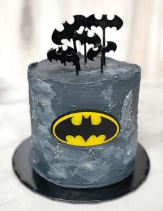 a batman themed cake with black icing and yellow bat symbols on it's top