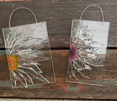 two clear bags with flowers on them are sitting on a wooden surface and one has a flower in it