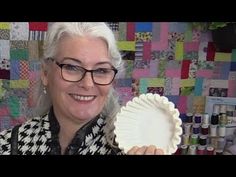 a woman holding a paper plate in front of a quilt