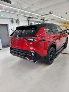 the rear end of a red toyota rav parked in a garage with other cars