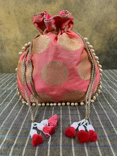 "Beautiful silk potli bag made with gold printing, pearl trim and red and white beaded tassels. It can be used as an evening purse,  a wedding favor or a drawstring gifting bag for a special gift!  Size: 10.5 \" (h) x 9.5 \" (w) This potli bag adds a beautiful touch to any Indian or western outfit. It is made from  silk and has delicate gold printing. The pearl trim and red and white beaded tassels add a special touch to this little bag. It can even be used as a gorgeous wedding favor or even as Red Bag With Zari Work For Festivals, Festive Red Zari Work Potli Bag, Elegant Potli Bag With Gota Work For Celebrations, Red Potli Bag With Zari Work For Diwali, Traditional Potli Bag With Dori Work For Celebration, Red Zari Work Potli Bag For Diwali, Traditional Potli Bag For Celebration With Dori Work, Traditional Potli Bag For Navratri Celebration, Red Festive Bag With Zari Work