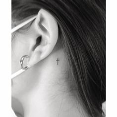 a woman's ear with a cross tattoo on it