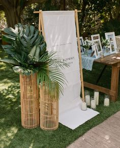 an outdoor ceremony setup with candles and pictures on the wall, palm tree in vases